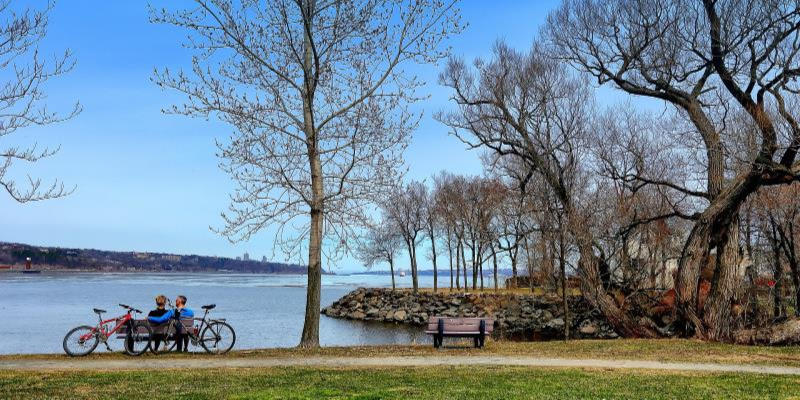 a couple sitting on a bench with bicycles nearby