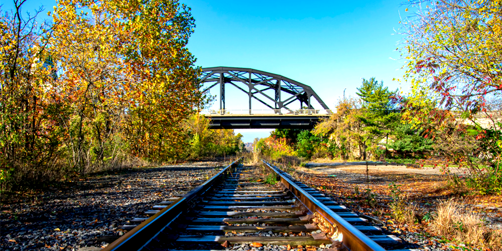 railroad tracks with a bridge in the background